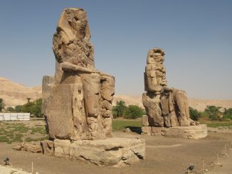 Die Kolosse von Memnon sind zwei ägyptische Giganten. Links in Kniehöhe sieht man eine wesentlich kleinere menschliche Figur und im Sockel noch kleinere Menschen. Foto (C) Silke Baron / flickr CC BY 2.0