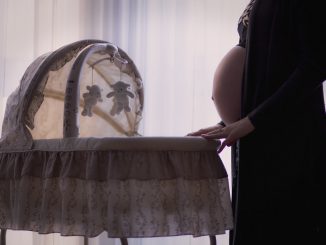 Schwangere Frau mit Stubenwagen